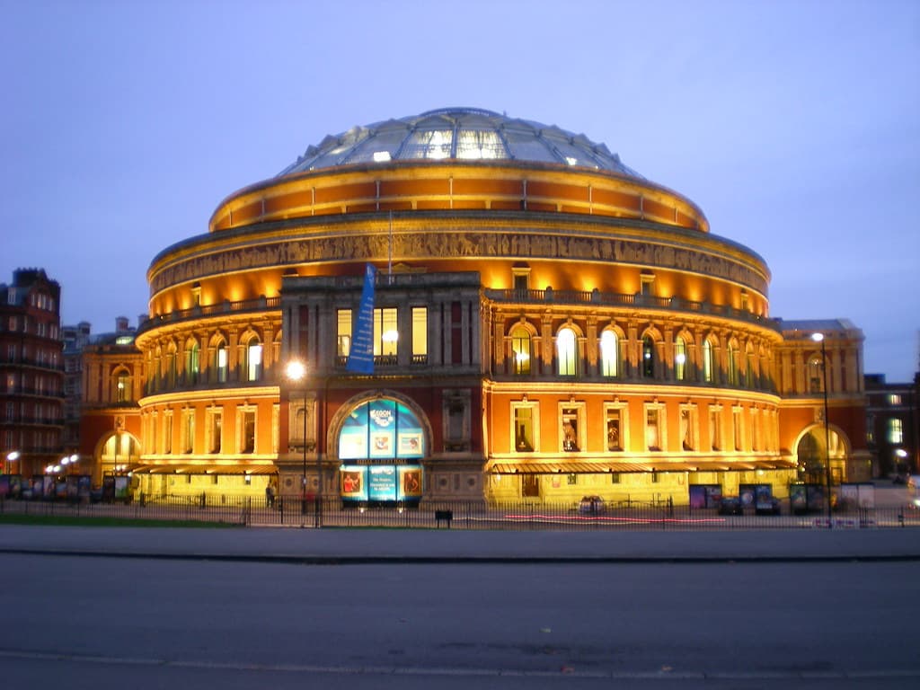 A large choir and orchestra performing in a grand concert hall