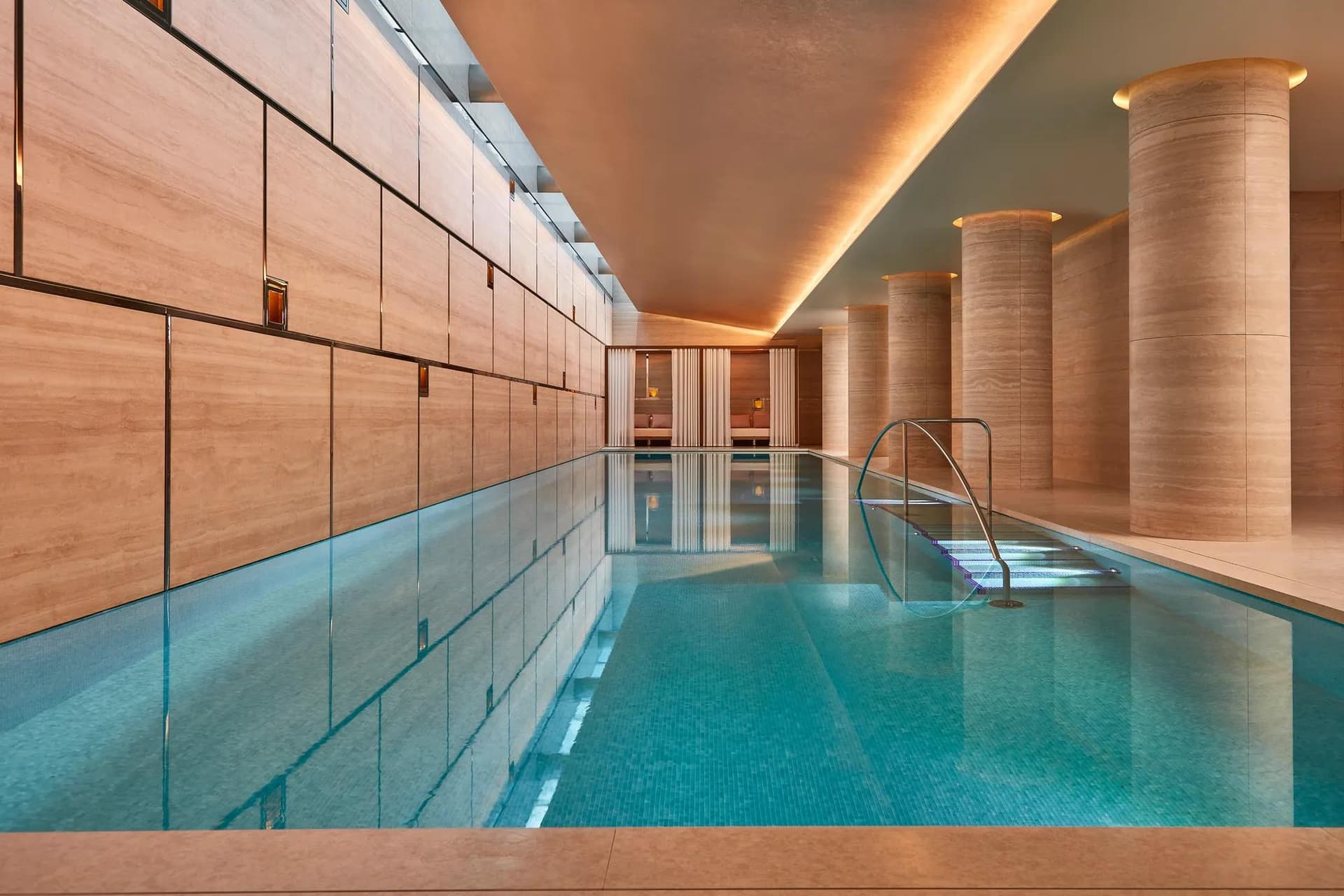 A calm indoor swimming pool with stone columns and soft lighting