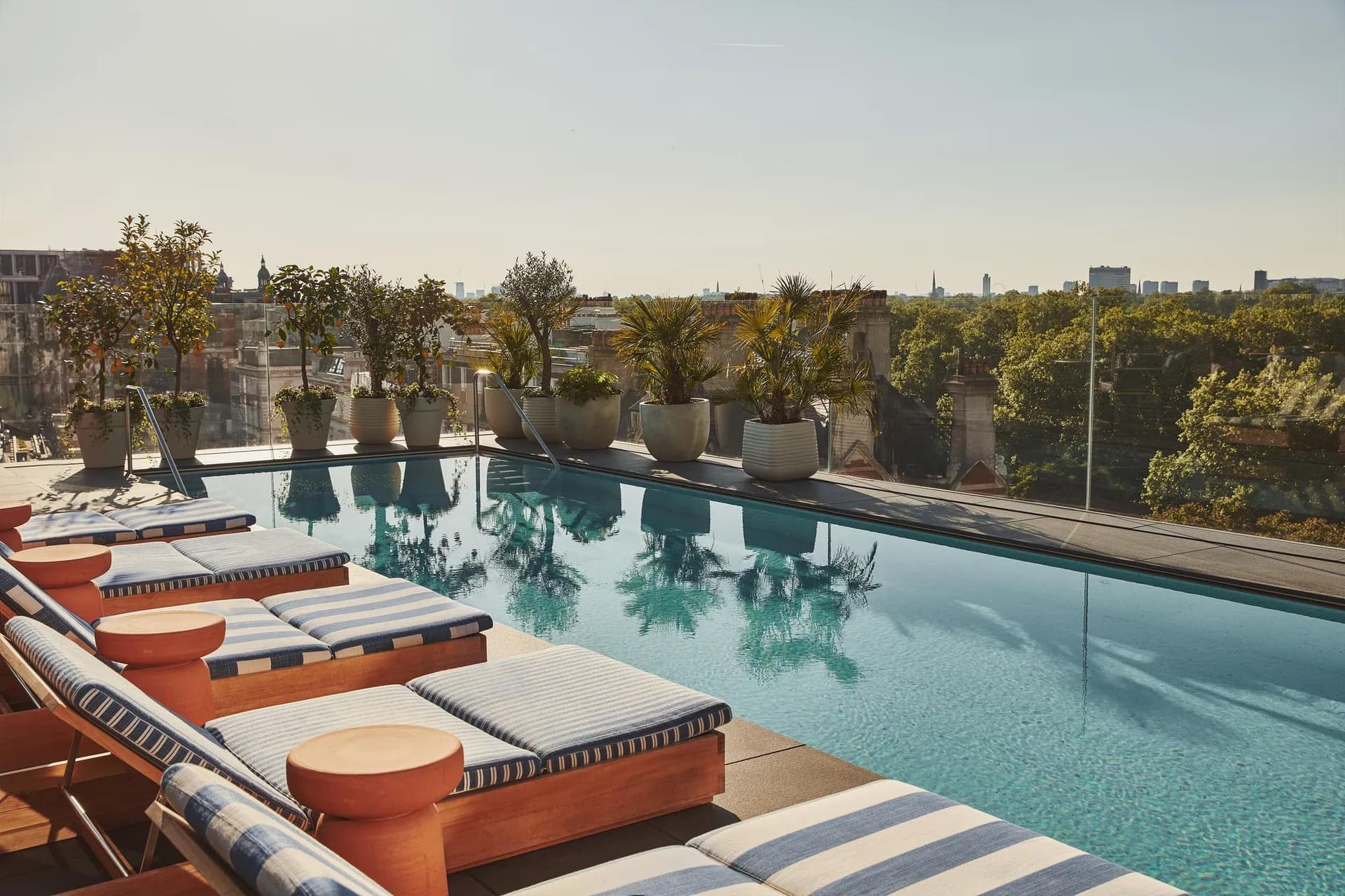 Cocktails on a sunny hotel rooftop terrace beside a pool in London