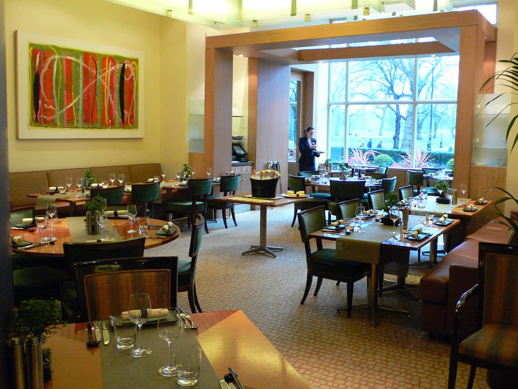 Lunch tables on a leafy hotel terrace overlooking a London park in summer