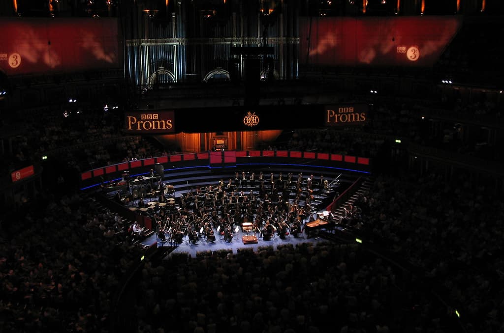 An orchestra performing to a full audience in a grand circular concert hall