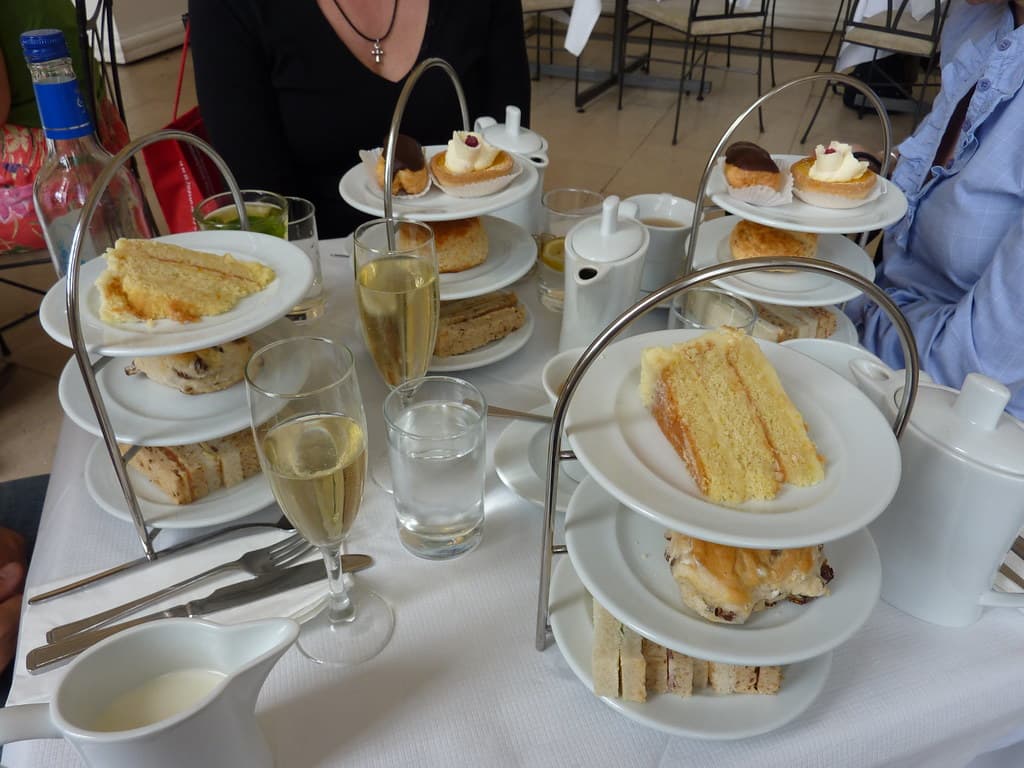 A tiered afternoon tea stand with scones, sandwiches and small cakes on a table