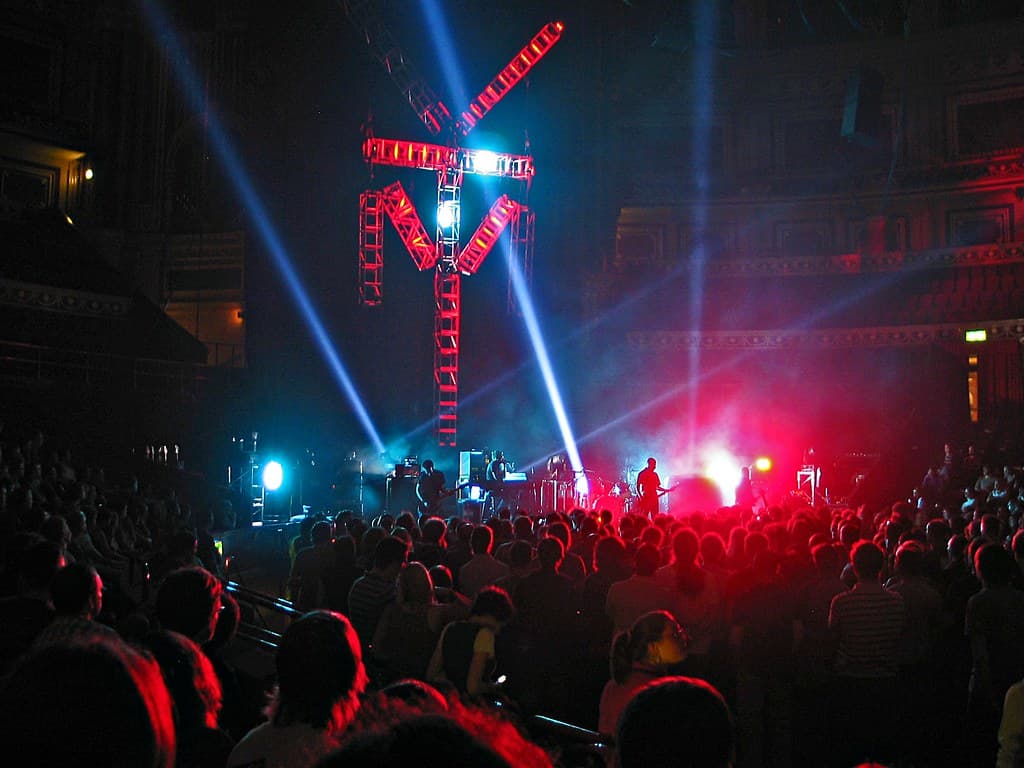 An opera singer performing in a spotlight in front of an orchestra