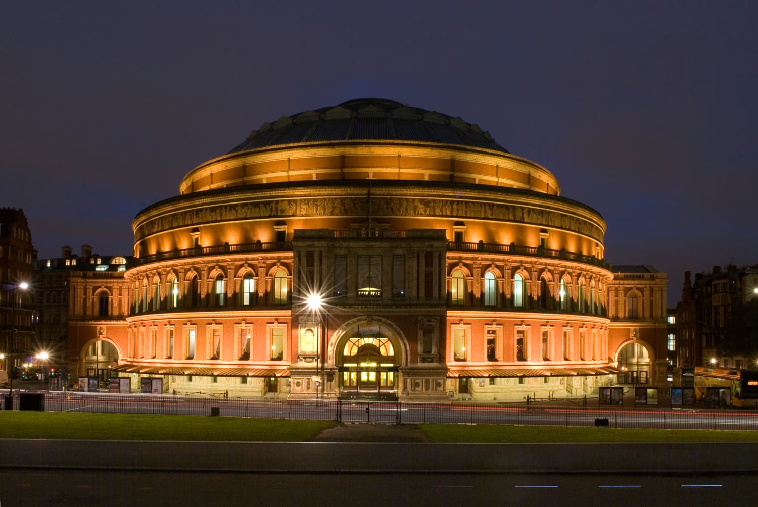 An orchestra performing on a lit stage in a grand concert hall